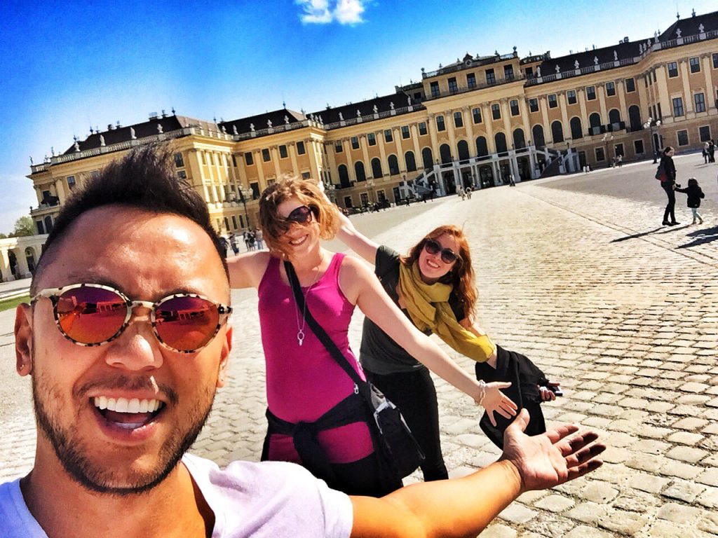3 people posing in front of a gorgeous building