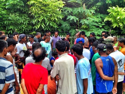 A circle of Philippino men selecting the competing roosters for the afternoon's cock fight