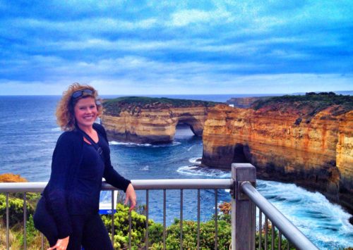 Female posing with stunning rock formations, including a rock arch, in the ocean