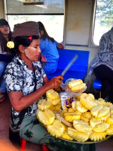 A Burmese woman cutting up pineapple on the train