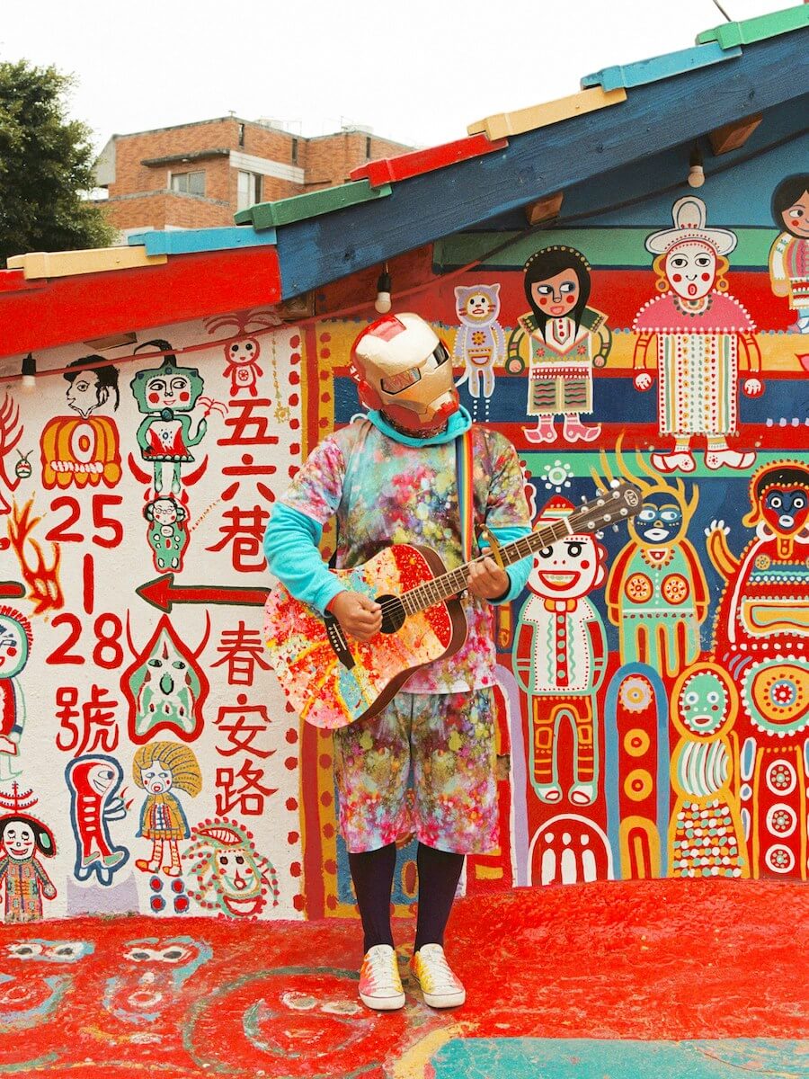 Colorful house covered in graffiti with a guitarist dressed up in front of it - Taken in Rainbow Village, Taichung, Taiwan