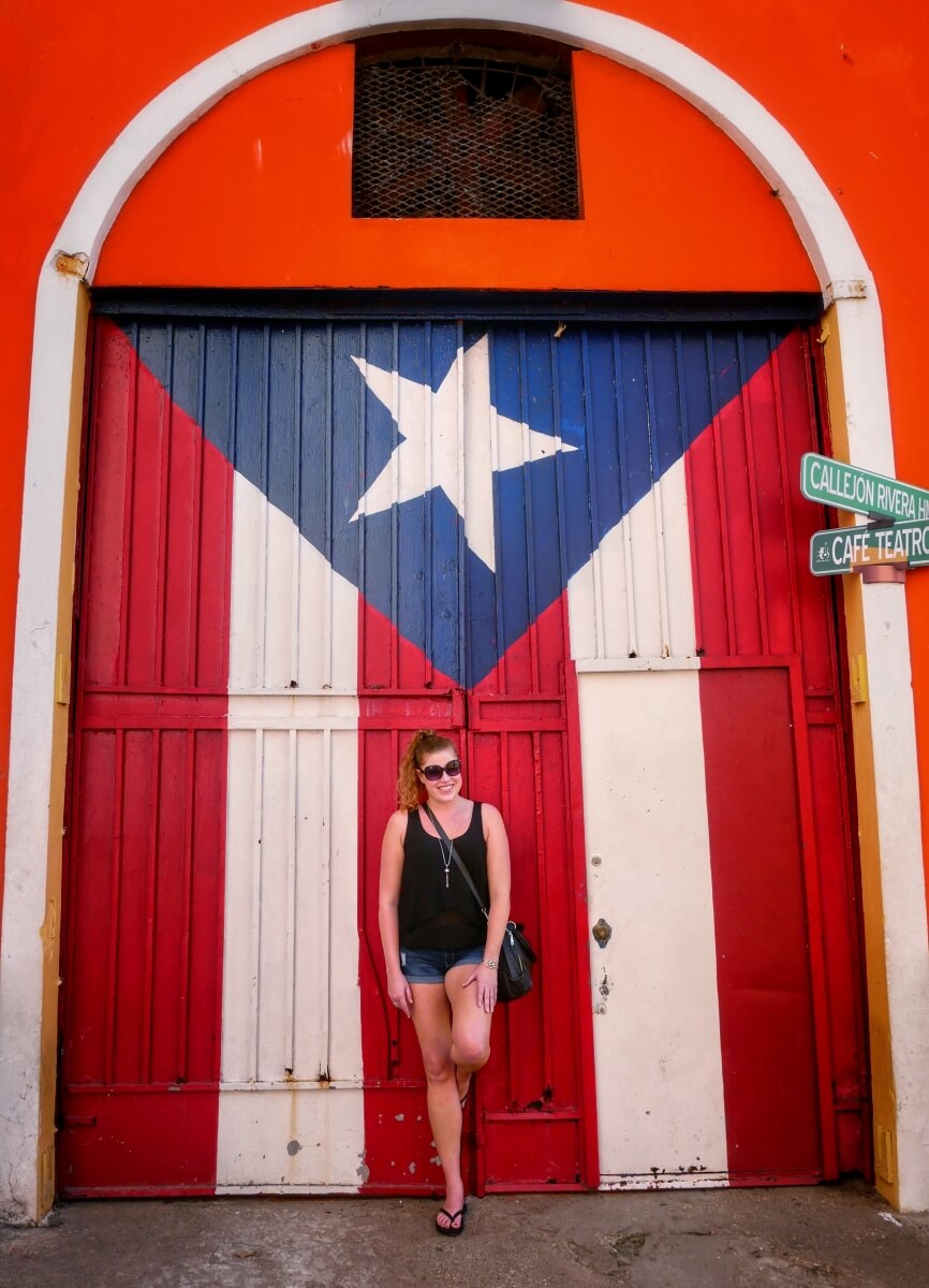 Girl posing with doors painted as the Puerto Rican flag