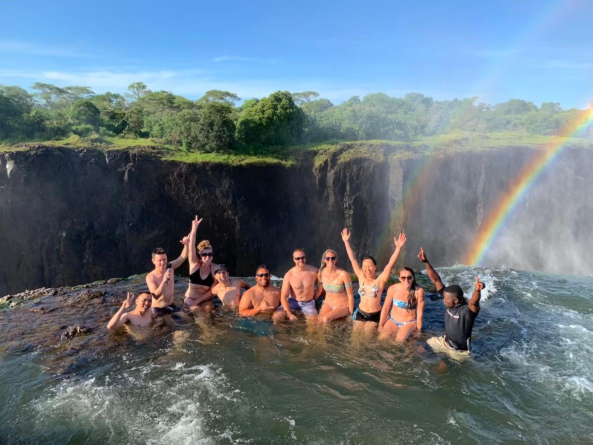 Group of tourists sitting on the edge of Devil's Pool