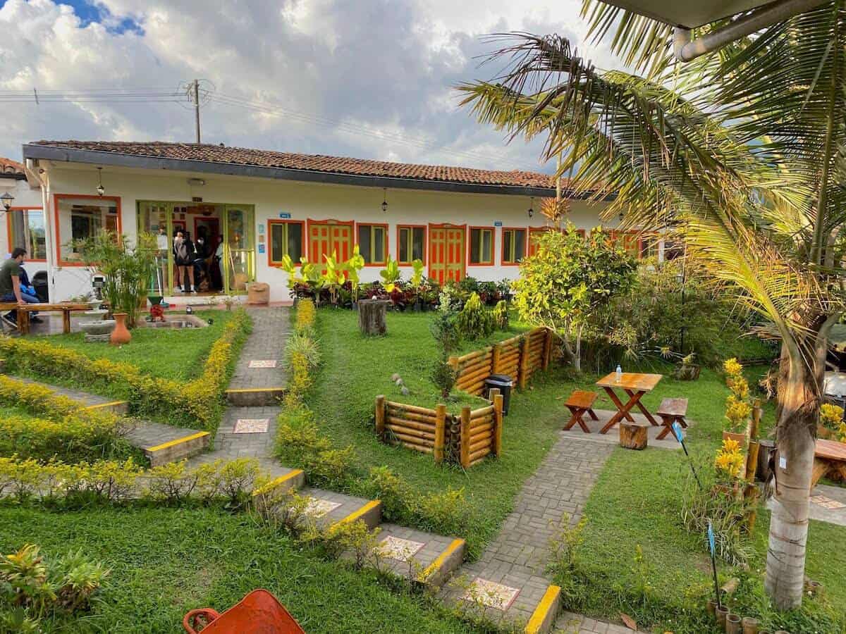 Colorful hostel with lush garden, outdoor seating, and tropical trees.