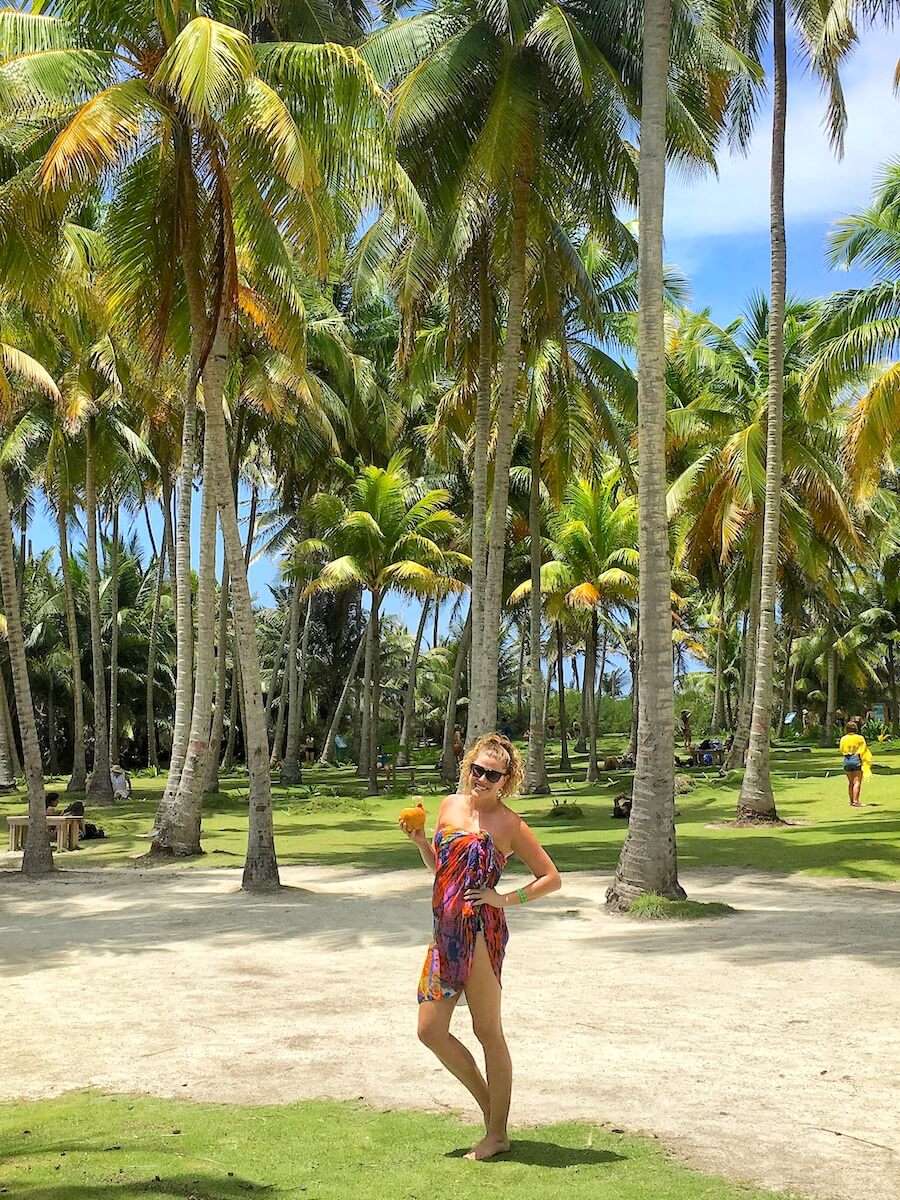 Julia drinking from a coconut in a palm tree field in Johnny Cay, San Andres, Colombia