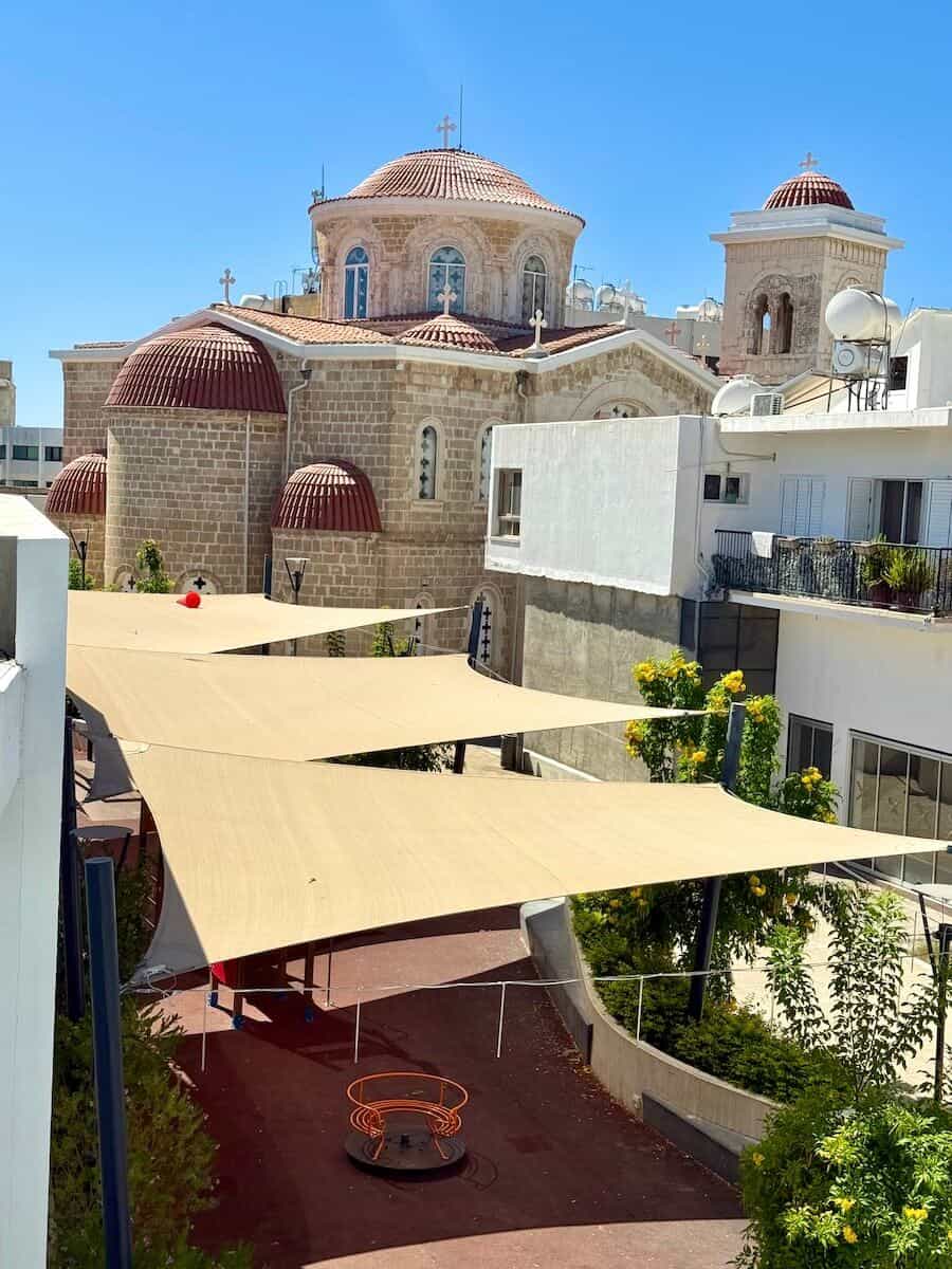Ancient church with domes and modern surroundings in Cyprus.