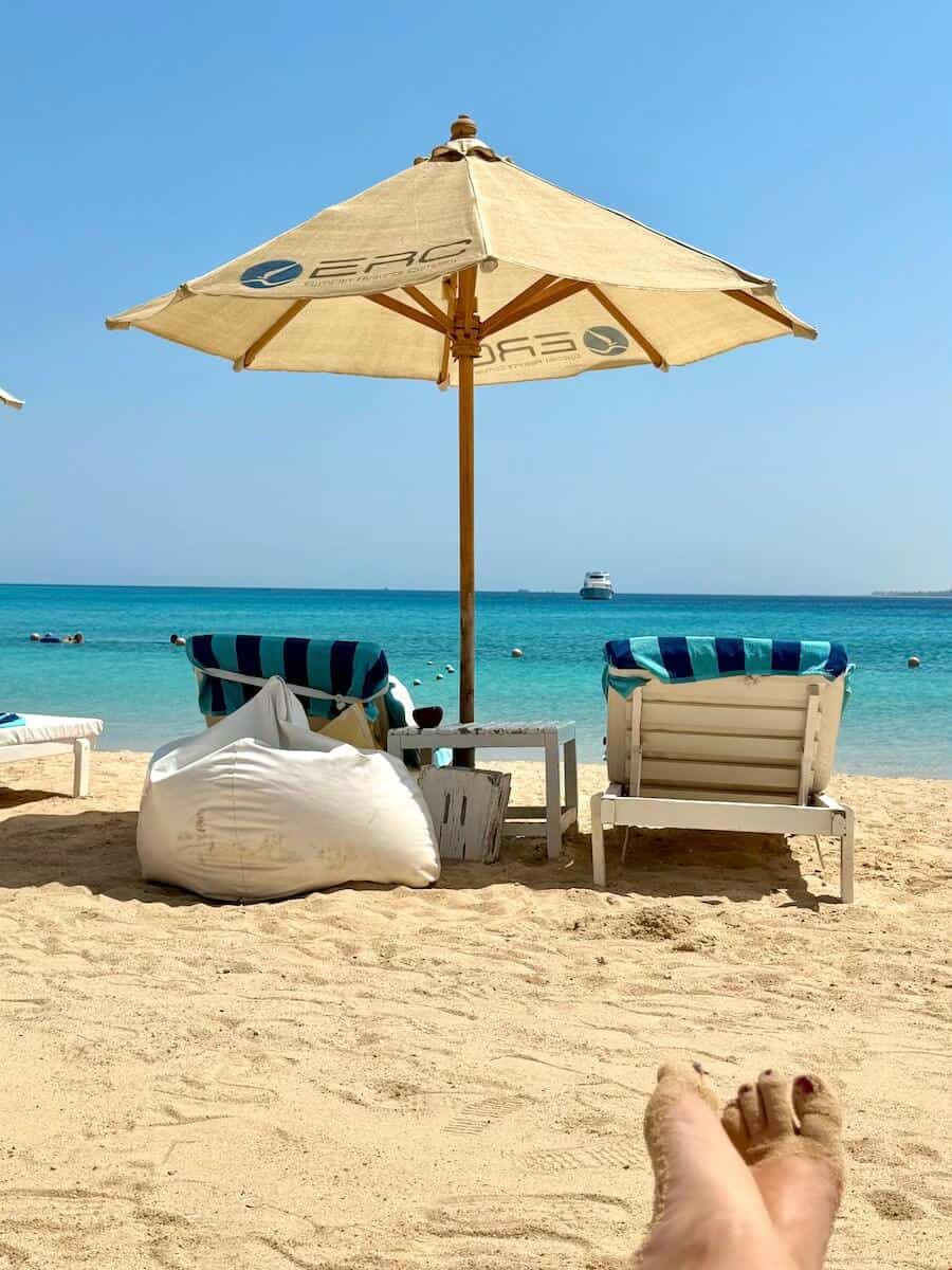 Beach scene with umbrella, lounge chairs, and ocean view.