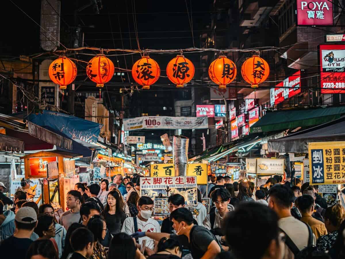 Vibrant Taipei night market with food stalls and shoppers.